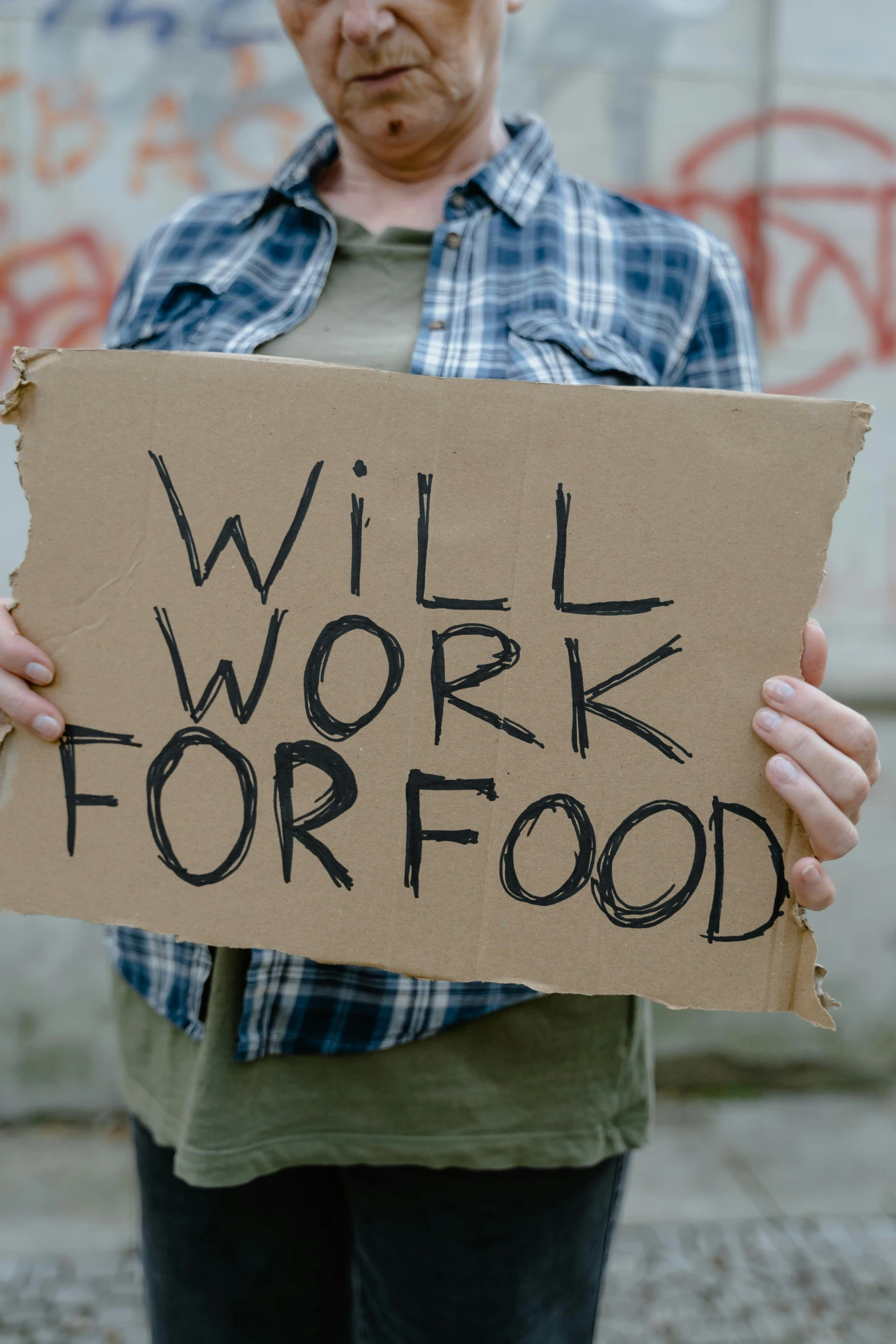 a man holding a sign saying will work for food