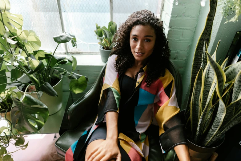 a woman is smiling sitting next to some potted plants