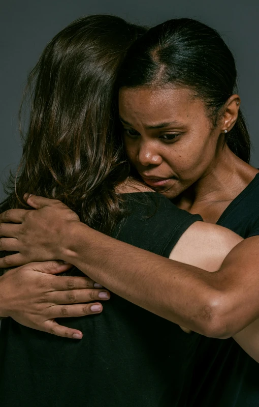 two women hug and stand together in the dark