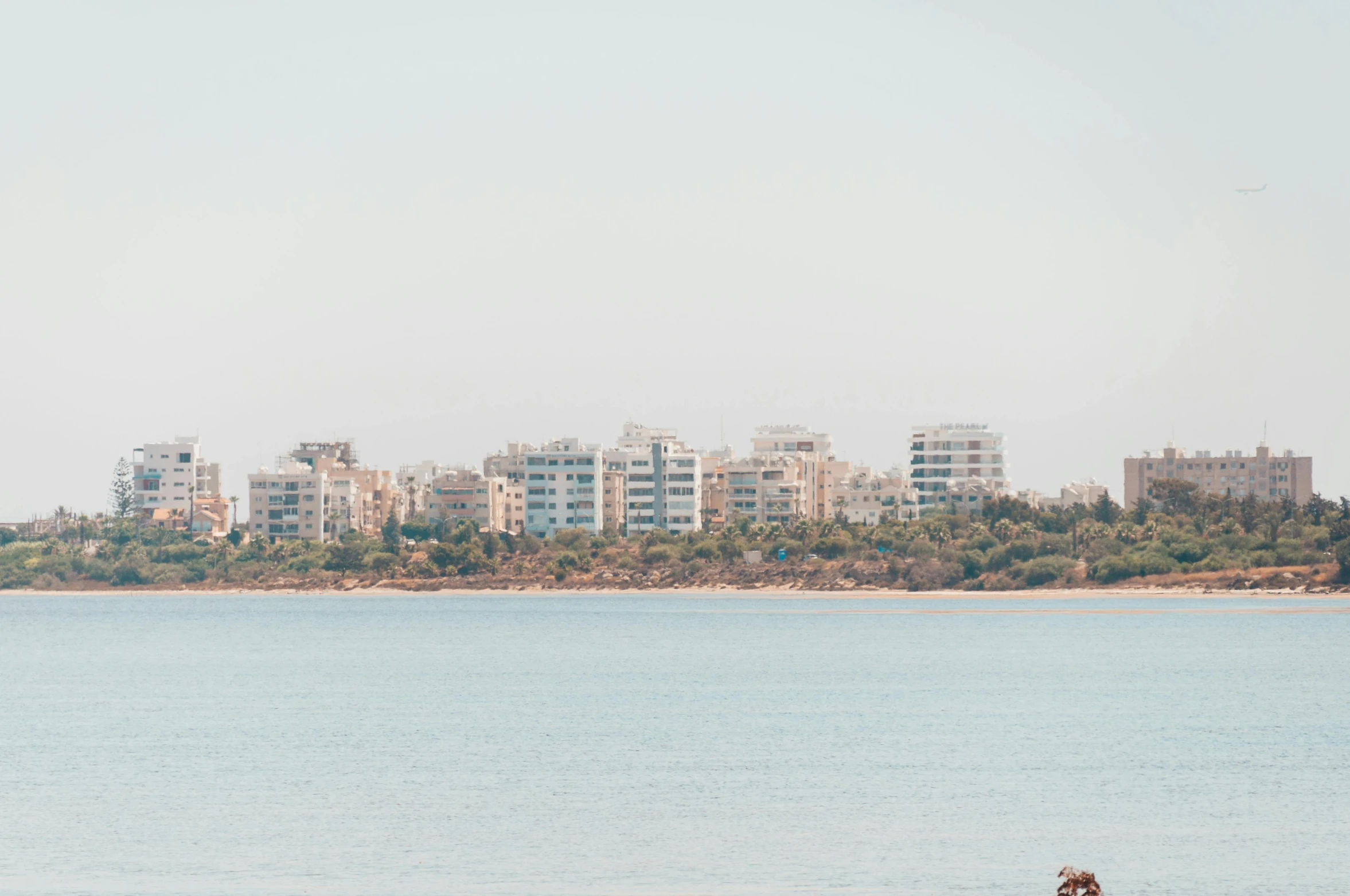 two people sit on the beach in front of a city