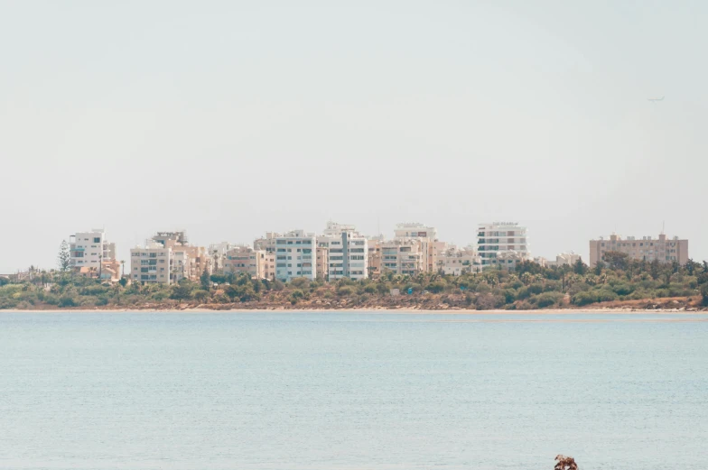 two people sit on the beach in front of a city