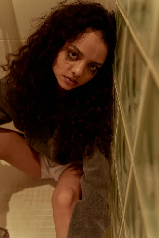 a young woman sits on the floor with her head down while crouching down