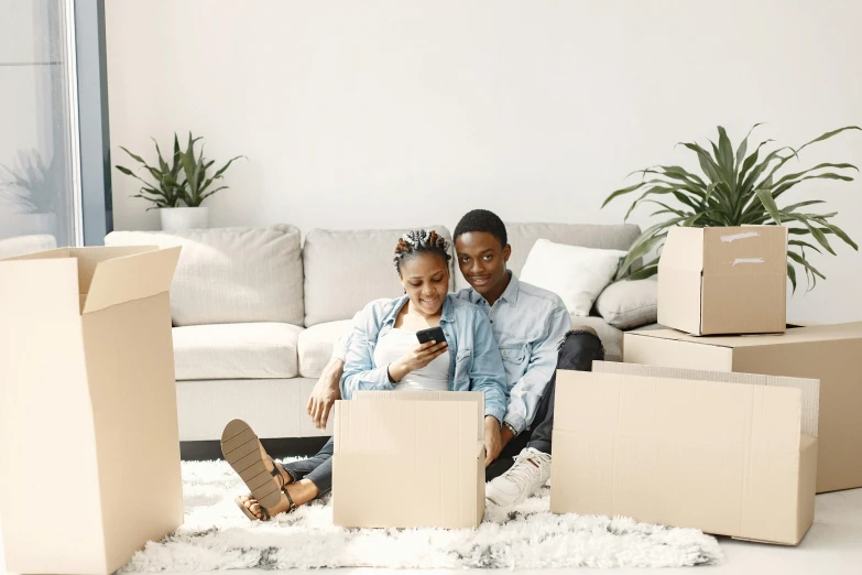 man and woman on the floor surrounded by boxes, texting