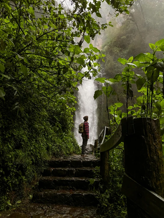 a person is standing at the bottom of steps in front of a waterfall