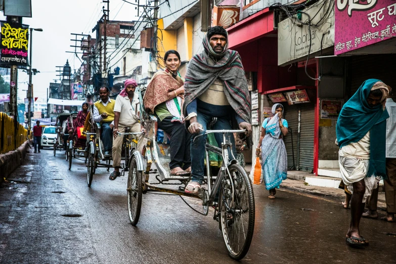 men riding bicycles down a narrow street in a slum city