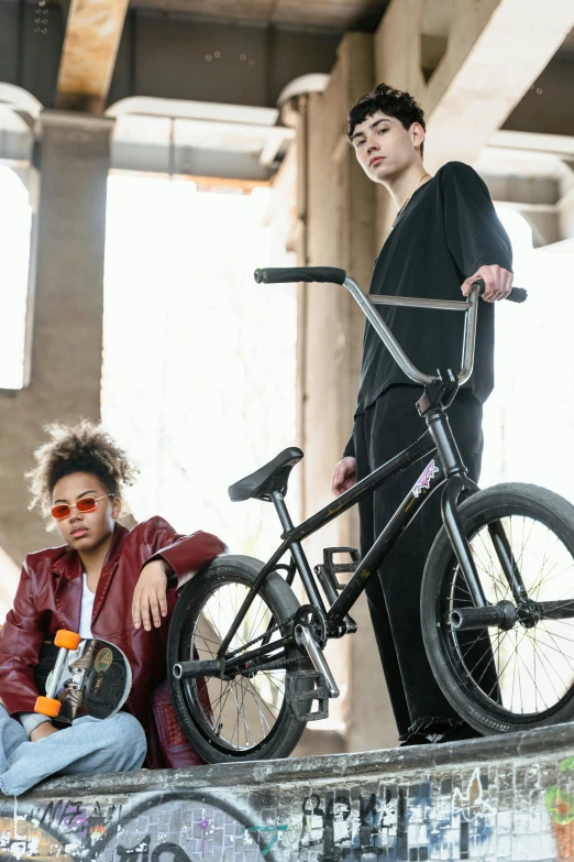 two boys are sitting on the side of a wall with their bicycles