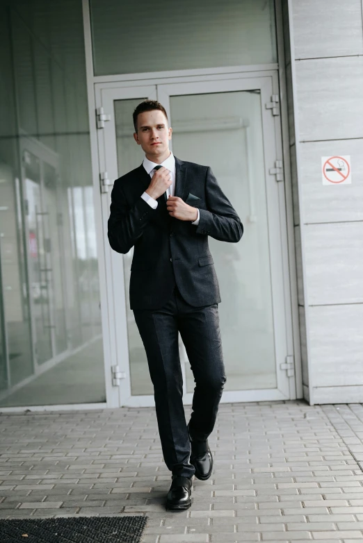 a man in black suit and white shirt posing for the camera