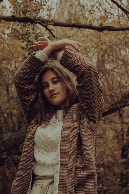 a  standing near a tree with her arms around her head