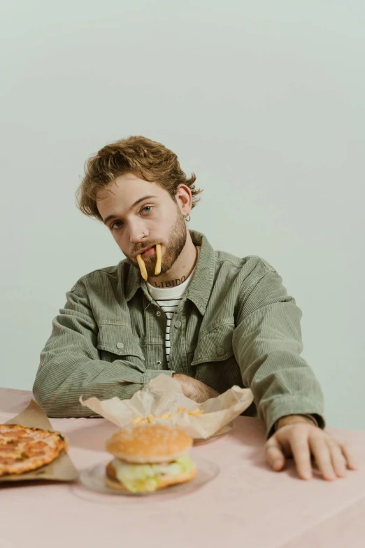 a young man is eating cheesesticks near a large sandwich