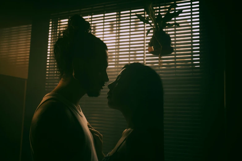 a man and a woman are standing near a window