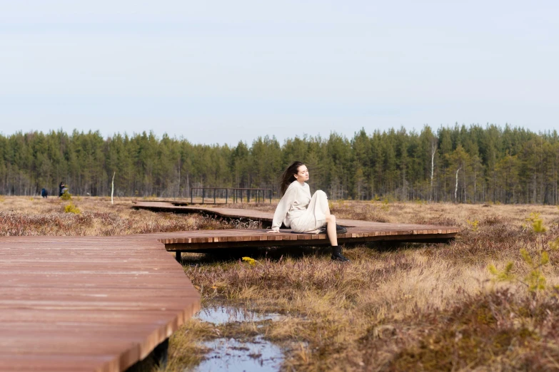 a woman is sitting by a dock and looks into the distance