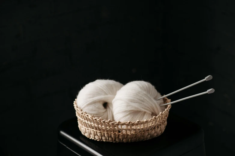 a wicker basket holds two balles of yarn