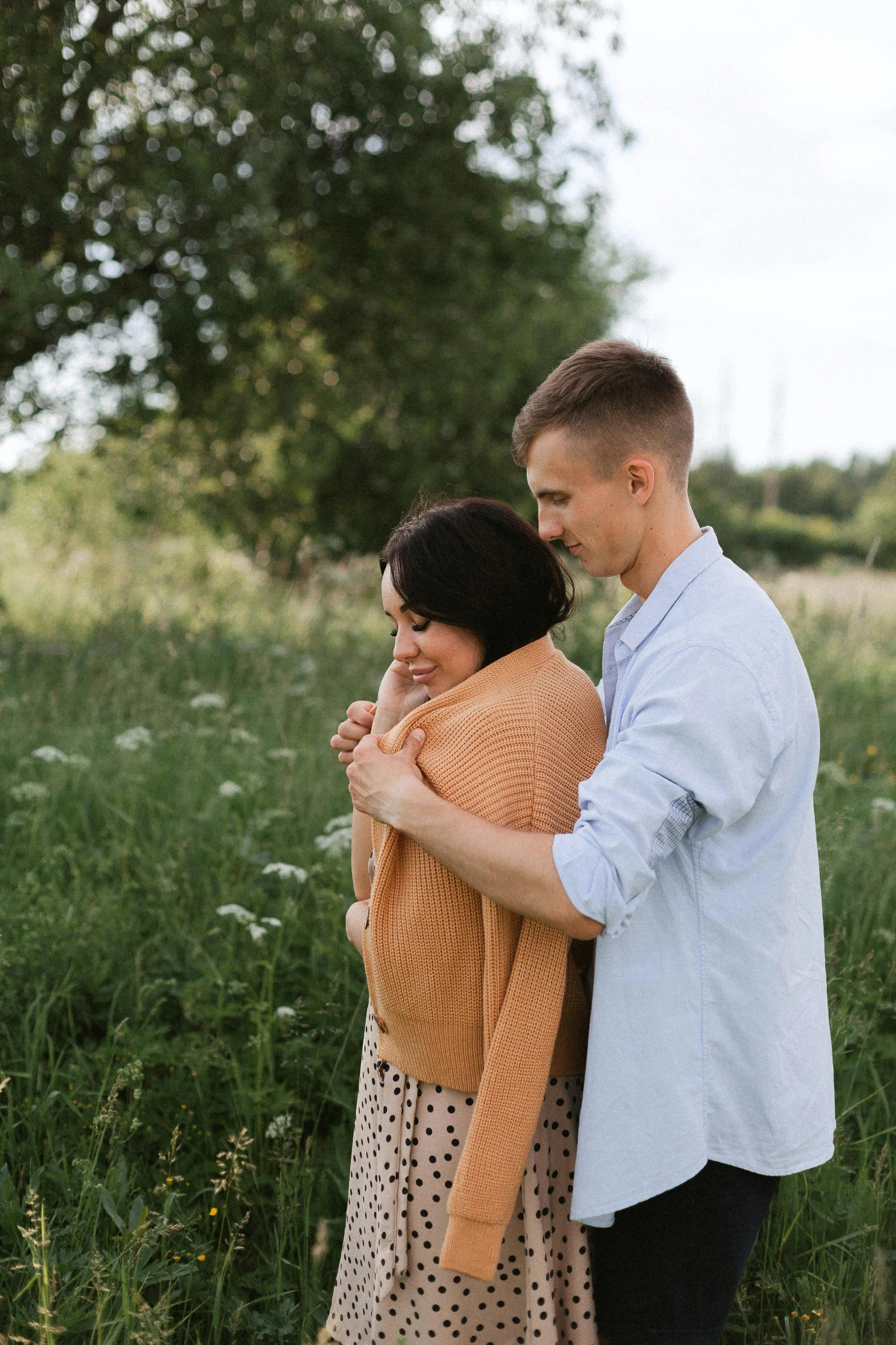 a man and a woman standing in some grass