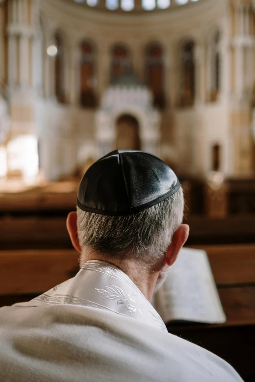 man wearing a hat sitting in the pews of a church