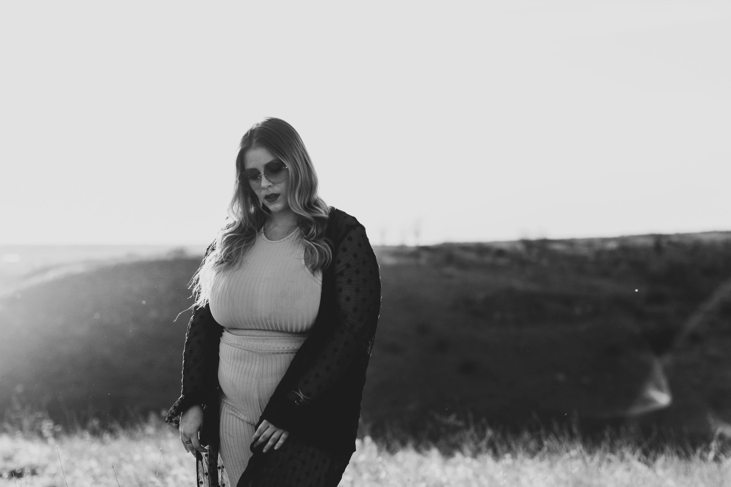 pregnant woman standing in an open field in the country