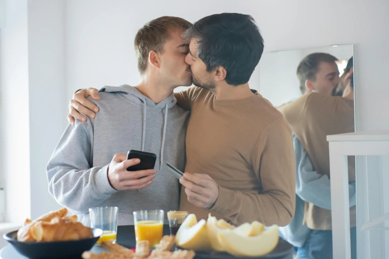 two men kissing each other over food on a table