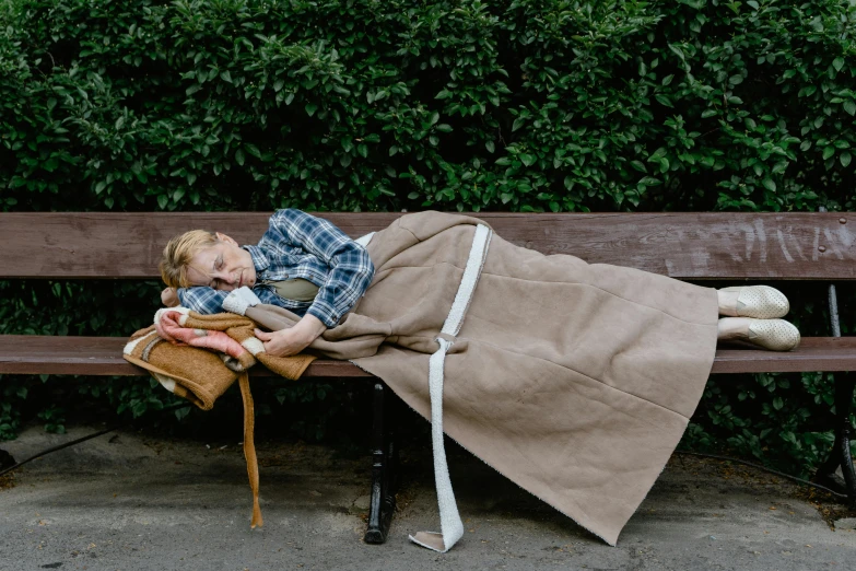 a child sleeping on a park bench holding an empty teddy bear