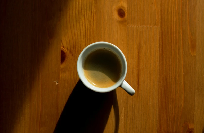 a cup of coffee sitting on top of a wooden table