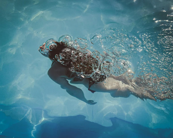 the person swims underwater in the clear blue water