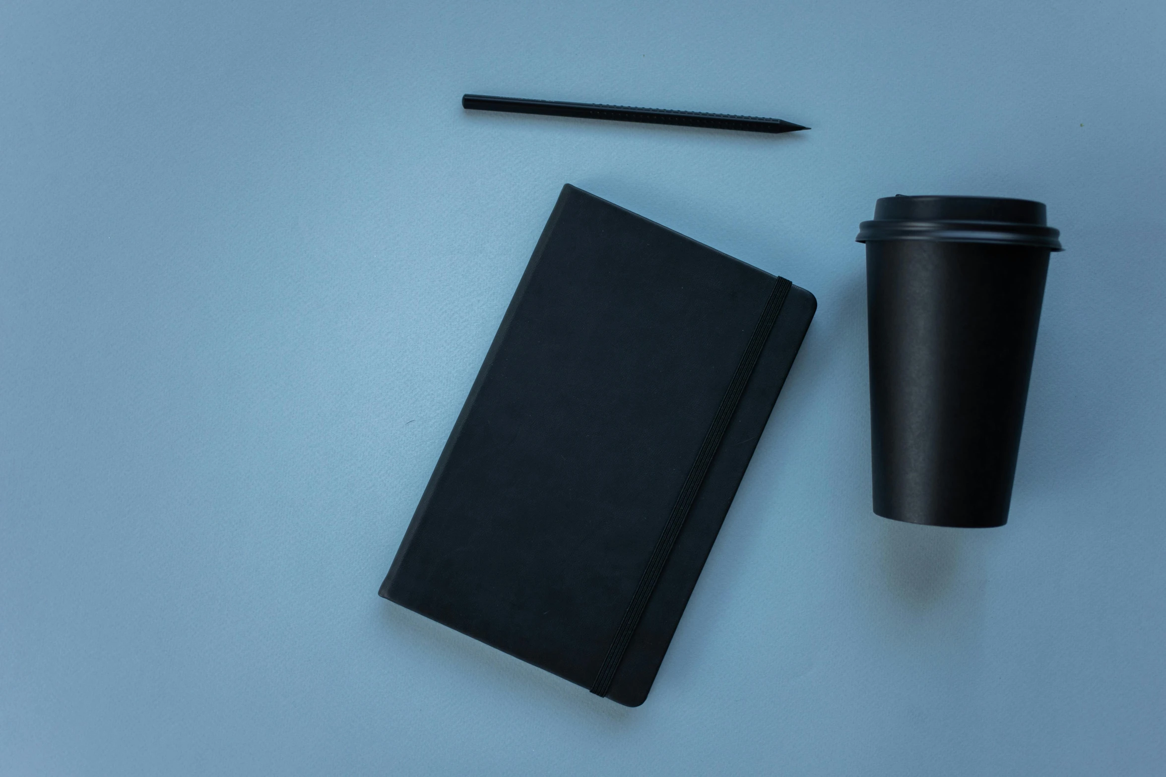 a black cup and a notepad, pencil and notebook