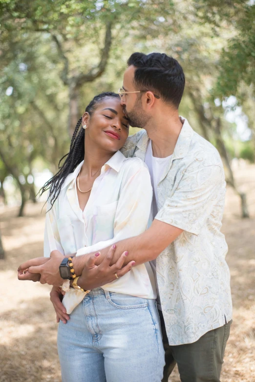 the man and woman are posing together in the woods