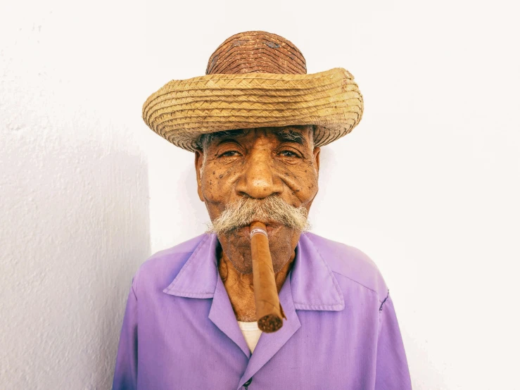 a man with a hat and tie holding a cigar