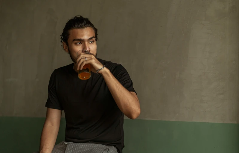 a man holding onto a brown cup and a drink in his hand