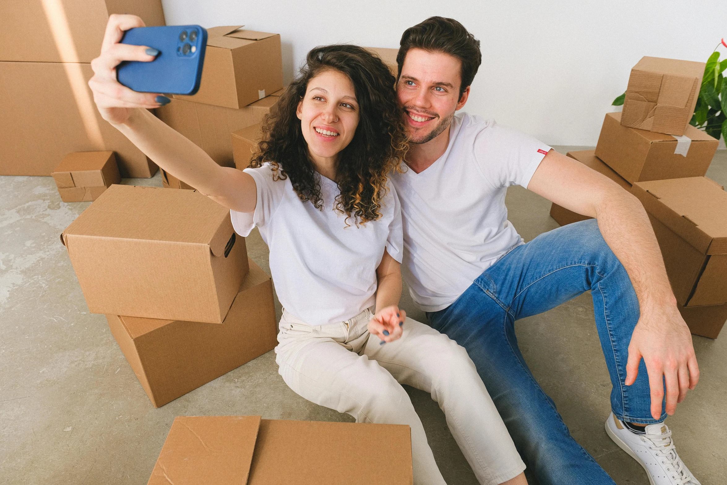 couple sitting in large stack of boxes with blue phone