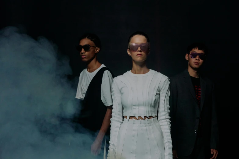 three people in white clothing are standing by smoke