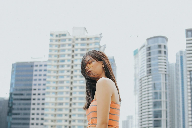 a girl standing with her  out and wearing an orange tank top and tan pants