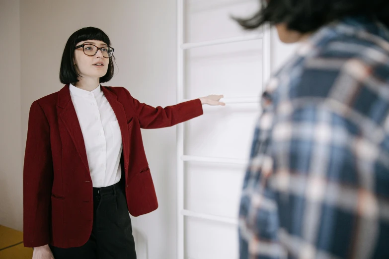 a woman points to a white wall with a picture on it