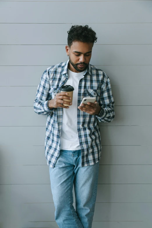 a man standing on a porch holding a cell phone and a cup