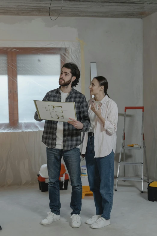 two people standing next to each other holding a sheet of paper