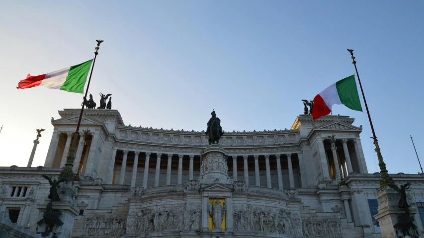 several italian flags fly near the top of a building