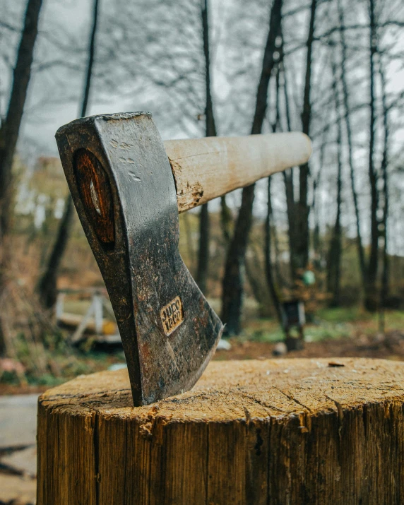 an old axe is stuck in to a wooden plank