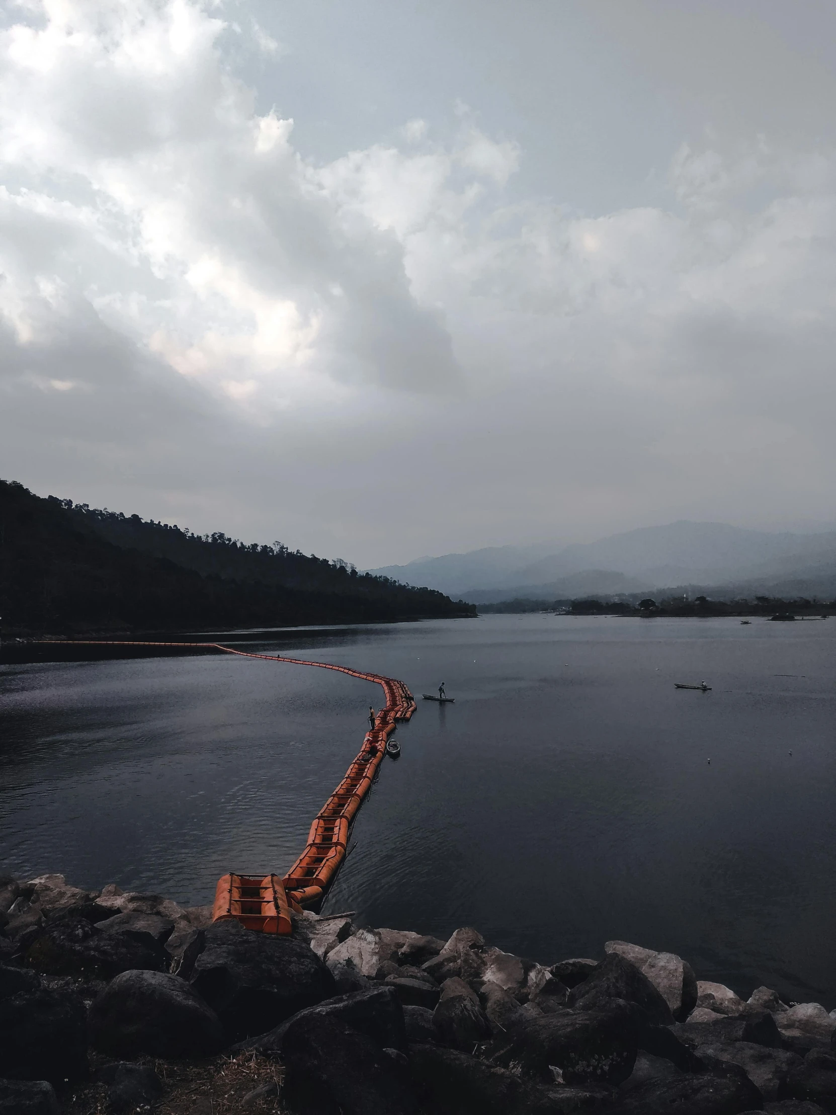 a pier on the edge of a lake surrounded by rocky shore