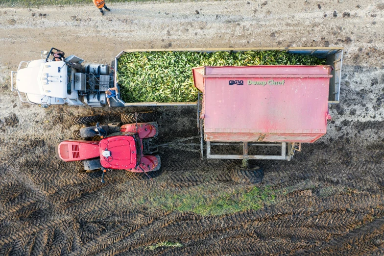 a truck carrying dirt and grass next to another tractor