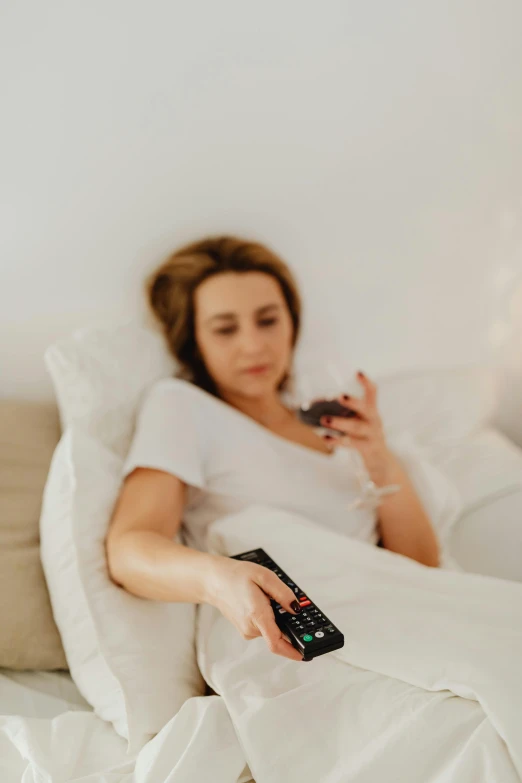 a woman in bed holding a remote control