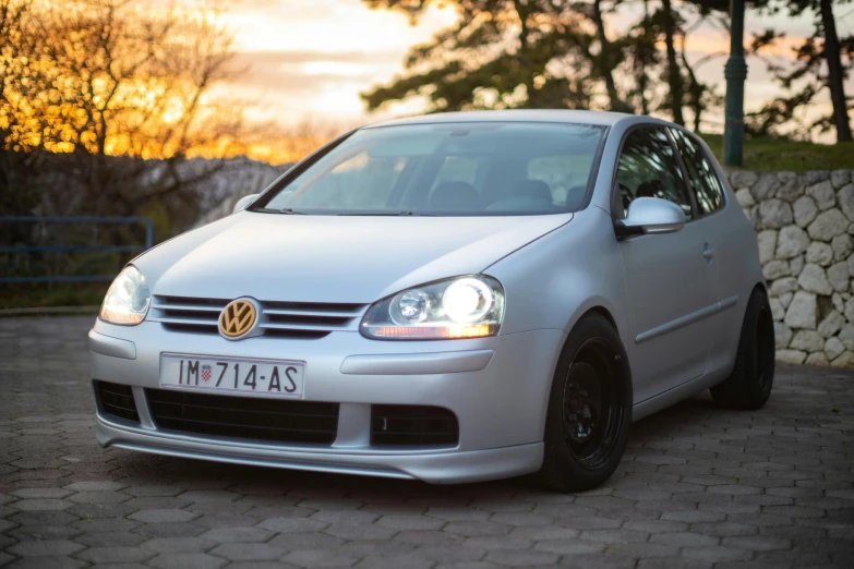 a silver vw golf with its headlights on