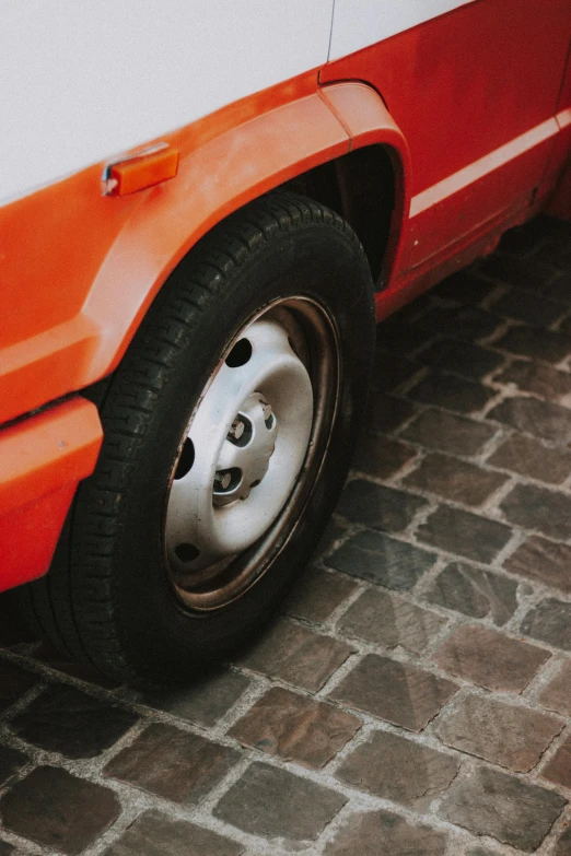 the wheel and tire of an orange car parked