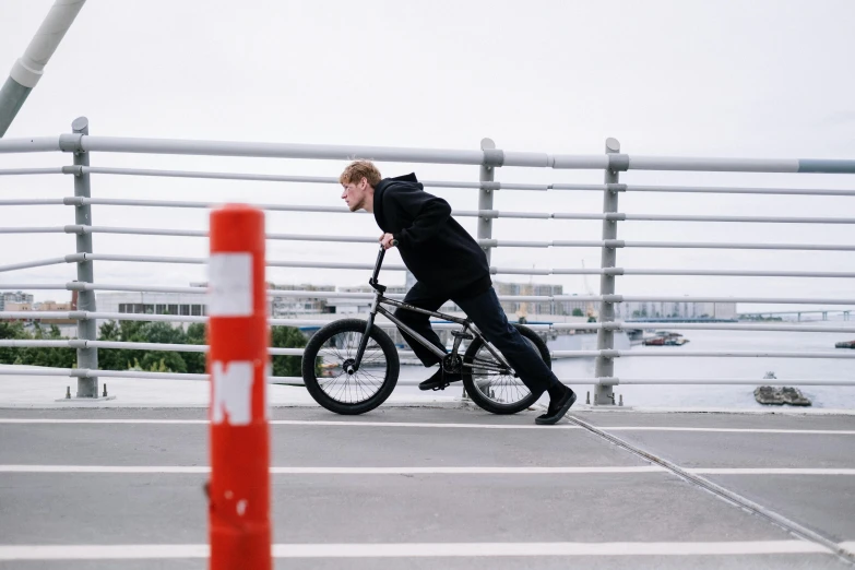 a young man riding a bike across a bridge