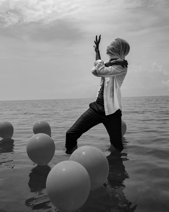 a man standing in the water surrounded by balloons