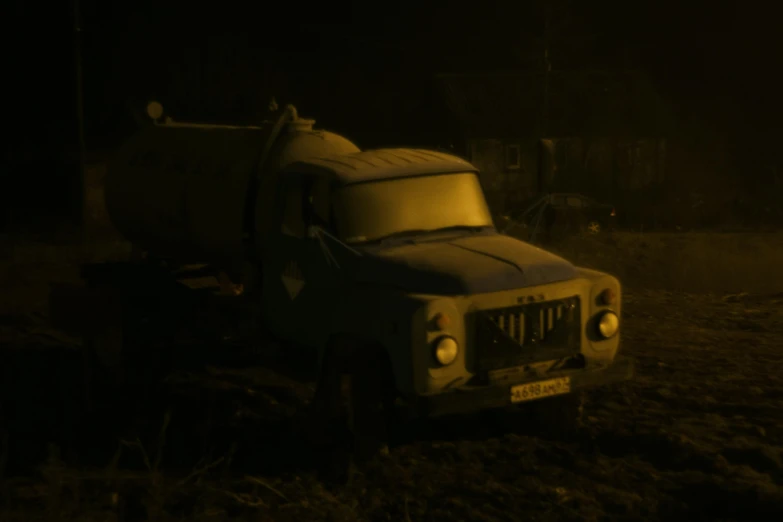 a dark truck parked in a field with a light on