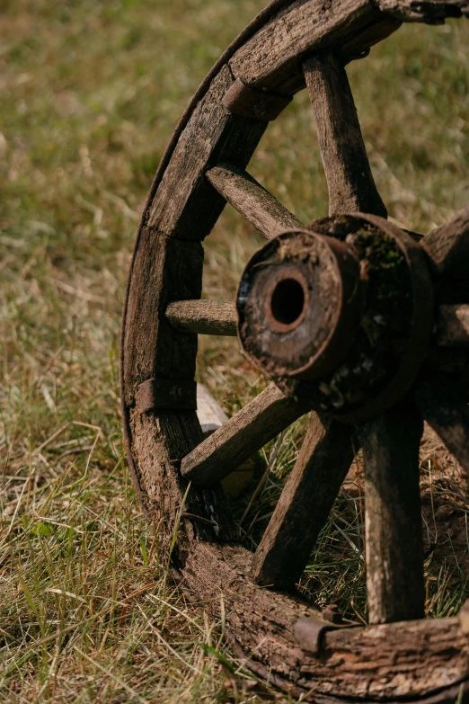 a broken wagon wheel on the ground near grass