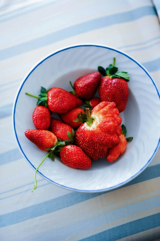 a bowl filled with red strawberries sitting on top of a table