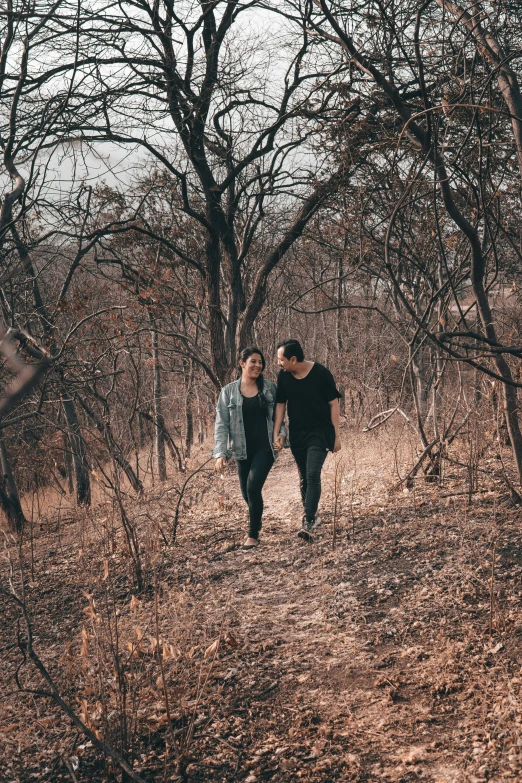 two people walking in a wooded area with bare trees