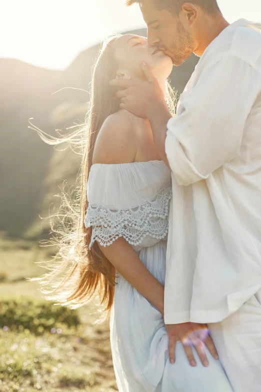 a beautiful couple standing close to one another in the middle of a field