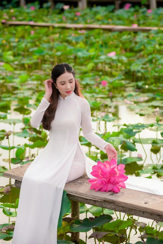 a woman sitting on a dock holding a flower