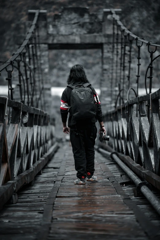 a person walking over a rusty bridge in the rain