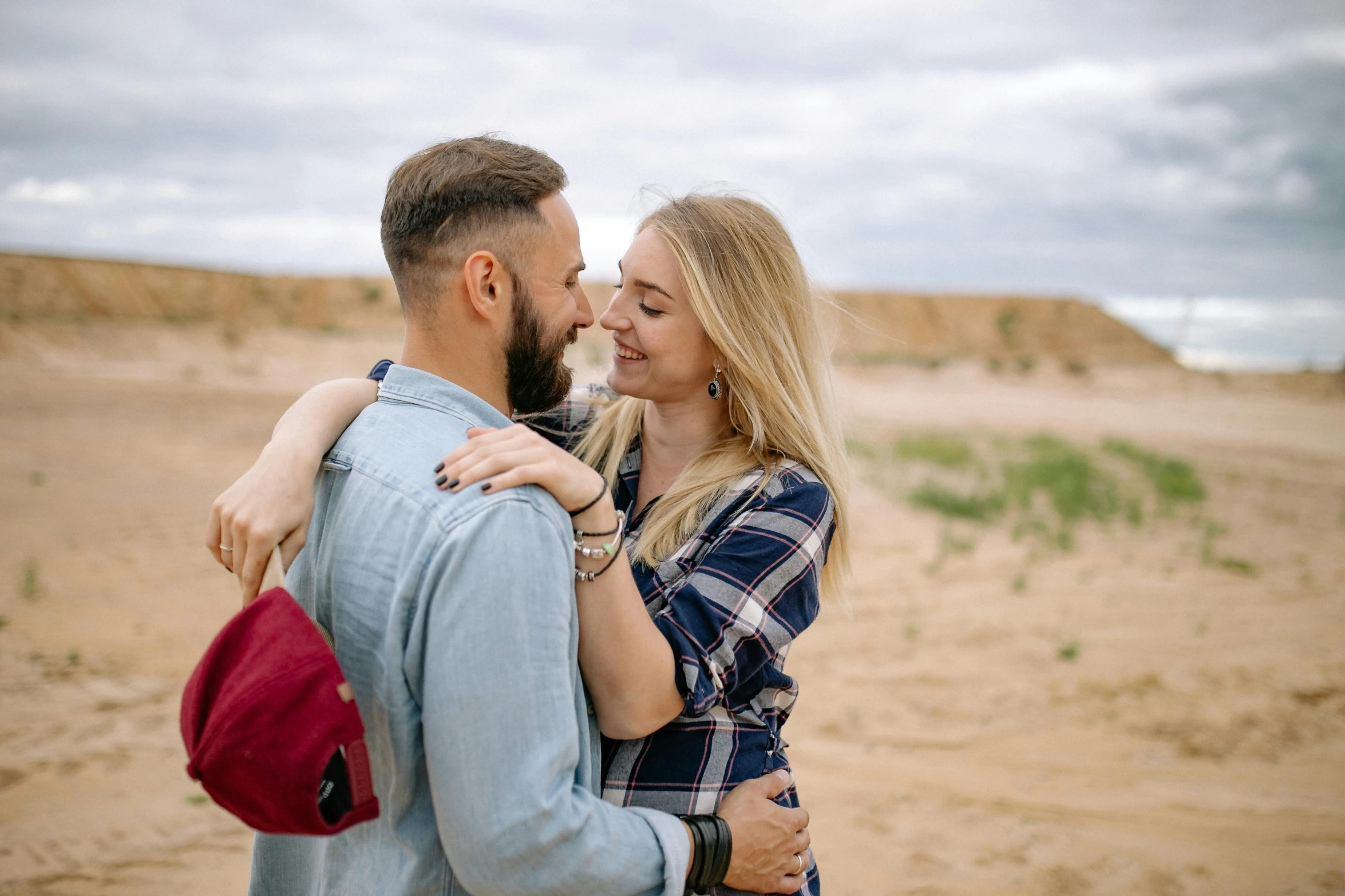 a man and woman smile and hug in the middle of a desert